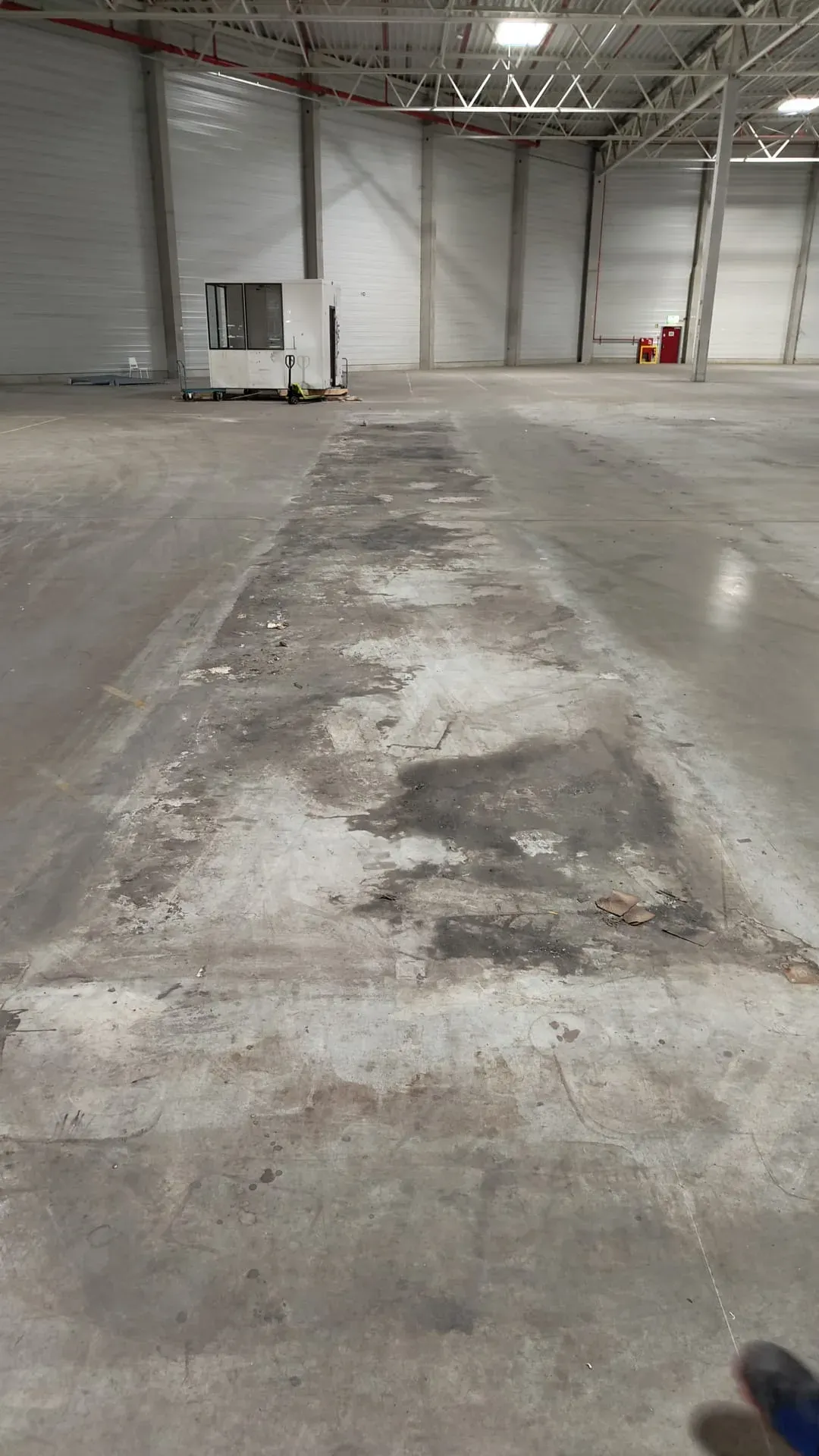 Hallenboden aus Beton mit eingefahrenen Öl- und Reifenspuren vor der Grundreinigung durch Gebäudedienstleistungen JULE